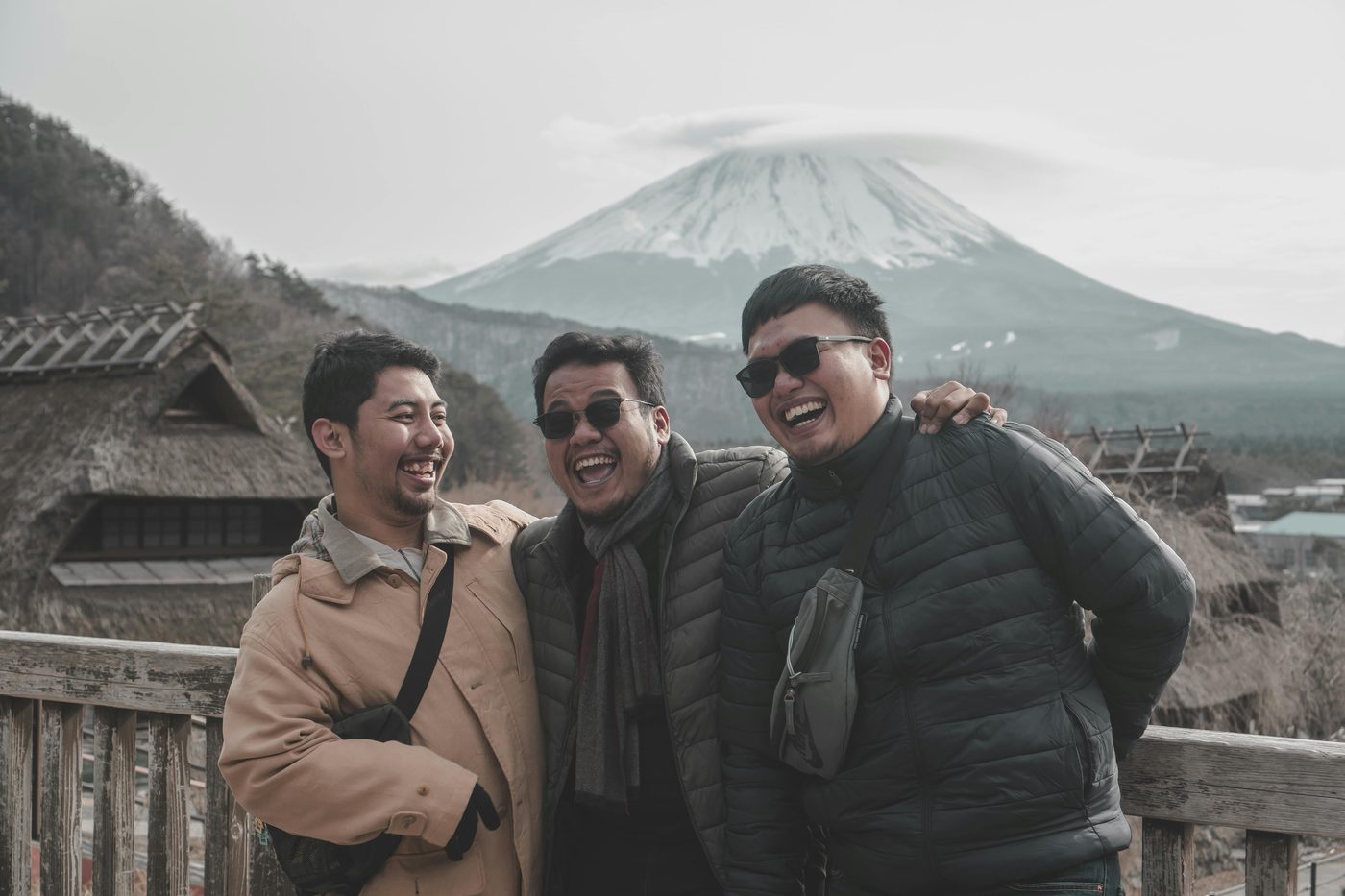 Three friends laughing together on a trip in front of a mountain